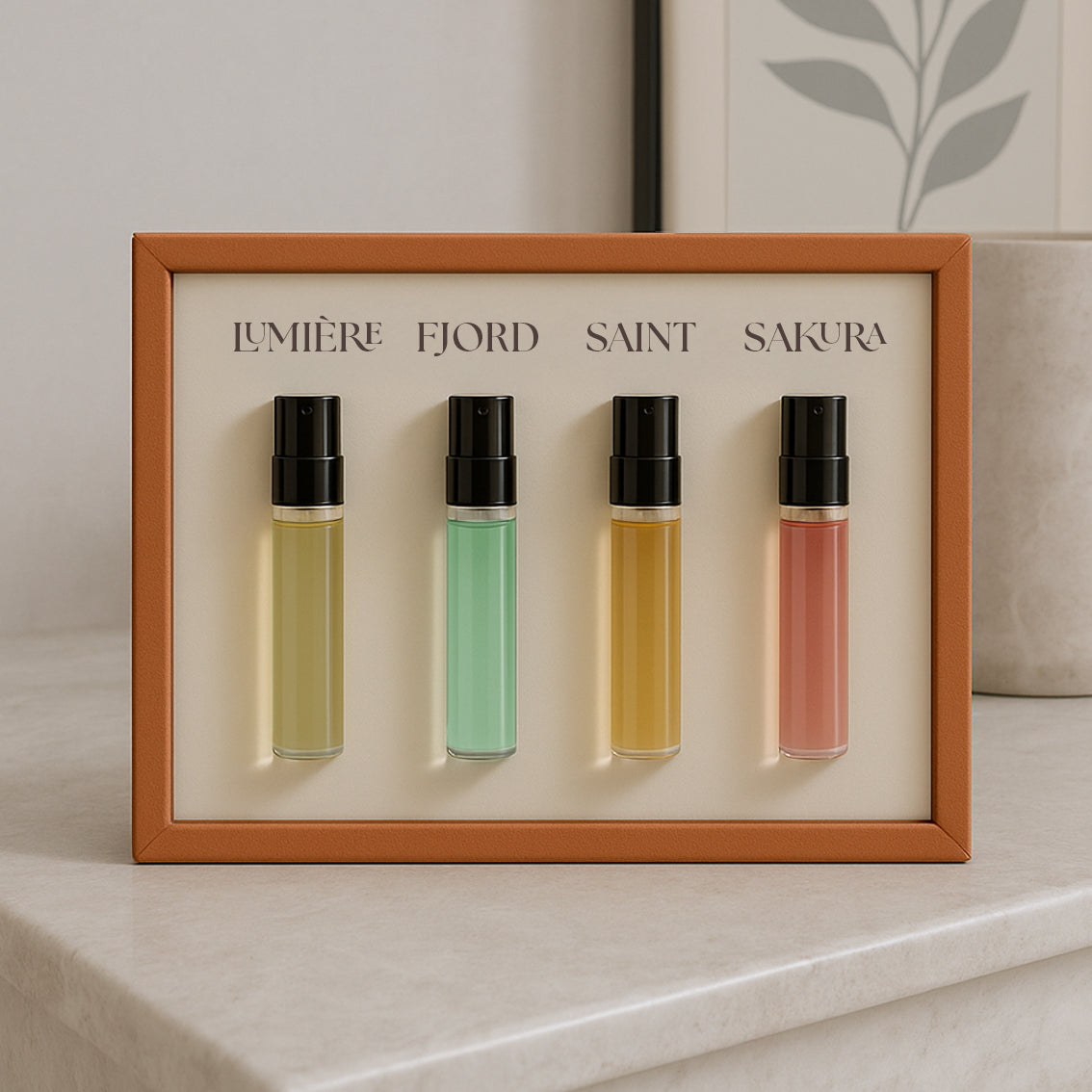 Le Scribe luxury perfume discovery set showcasing four unisex fragrances in an orange textured frame displayed on a marble surface in an elegant interior