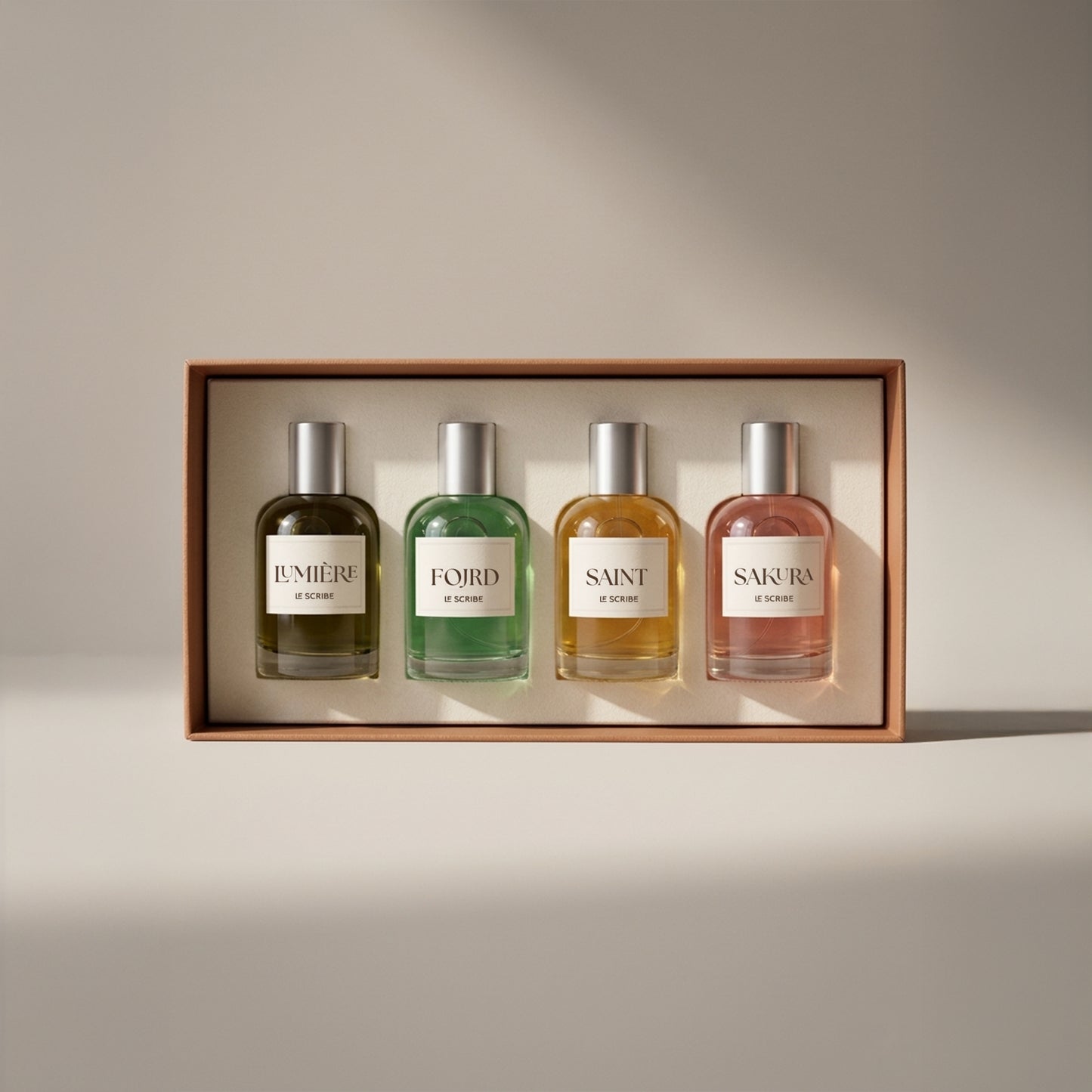 Le Scribe perfume discovery set with four 50ml fragrances — Lumière, Fojrd, Saint, and Sakura — displayed in a luxury presentation box on a neutral studio background.