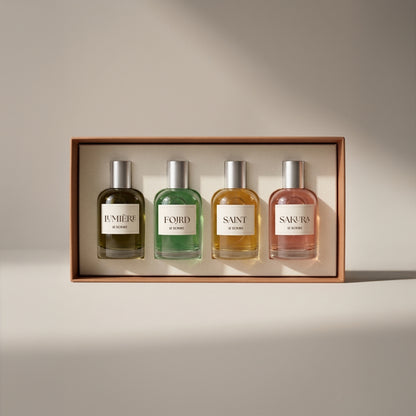 Le Scribe perfume discovery set with four 50ml fragrances — Lumière, Fojrd, Saint, and Sakura — displayed in a luxury presentation box on a neutral studio background.